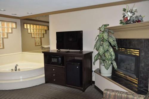 a bathroom with a tub and a tv on top of a fireplace at Ramada by Wyndham Abbotsford in Abbotsford