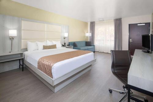 a hotel room with a bed and a desk and a television at Ramada by Wyndham Burbank Airport in Burbank