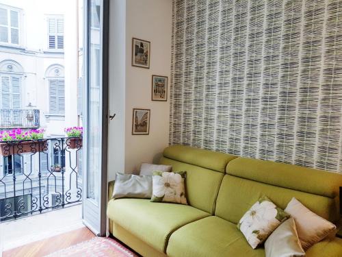 een groene bank in een kamer met een raam bij Madeleine apartments - Residenza Belle Époque in Milaan