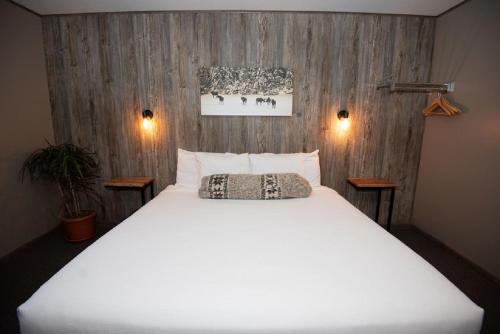 a large white bed in a room with wooden walls at Mountain Inn at Lutsen in Lutsen