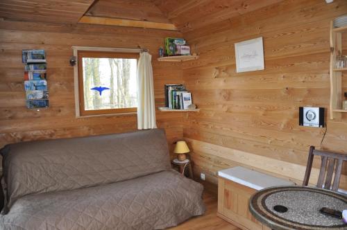 a bedroom in a log cabin with a bed and a window at La Cabane aux Secrets - Au Milieu de Nulle Part in Outines