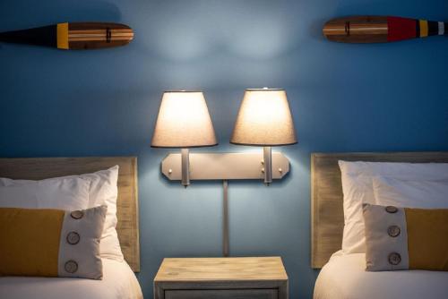 a bedroom with two beds and two lamps on the wall at Mountain Inn at Lutsen in Lutsen