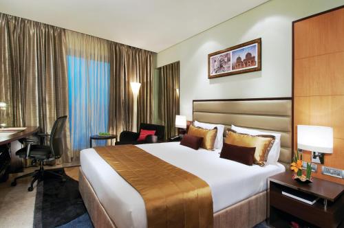 a hotel room with a large bed and a desk at Vivanta Hyderabad, Begumpet in Hyderabad