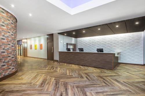 an office lobby with a reception desk and a brick wall at Ramada by Wyndham Tampa Westshore Airport South in Tampa