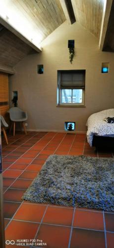 a room with a red tiled floor with a bed and a window at Le Durbuy Lodge in Durbuy