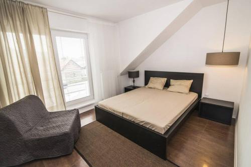 a bedroom with a bed and a chair and a window at Apartment Unimix in Liptovský Mikuláš