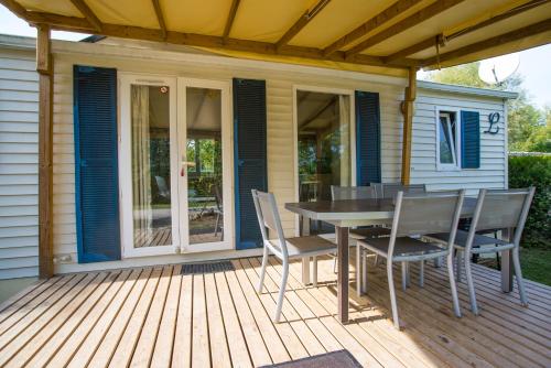 a patio with a table and chairs on a deck at Camping du Château Vert in Hondainville