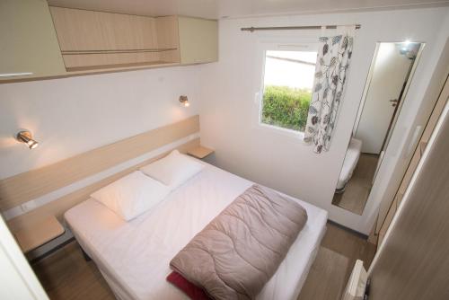 a small bedroom with a white bed and a window at Camping du Château Vert in Hondainville