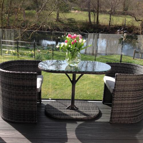 a glass table with a vase of flowers on a deck at Riverbank in Callander