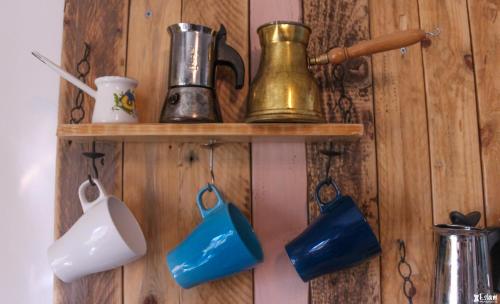 a wall with wooden shelves with tea pots and pitchers at The White Hill Guesthouse in Yeroẖam