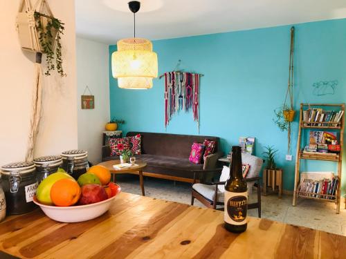 a living room with a bowl of fruit and a bottle of wine at The White Hill Guesthouse in Yeroẖam