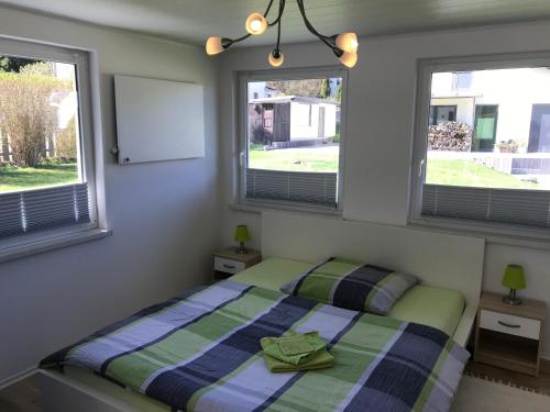 a bedroom with a bed and two windows at Ferienbungalow Grünbach in Grünbach