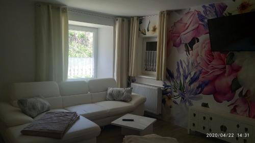 uma sala de estar com um sofá branco e uma janela em Gästehaus - Café Frank em Antweiler