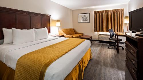 a hotel room with a large bed and a television at SureStay Hotel by Best Western Orange in Orange