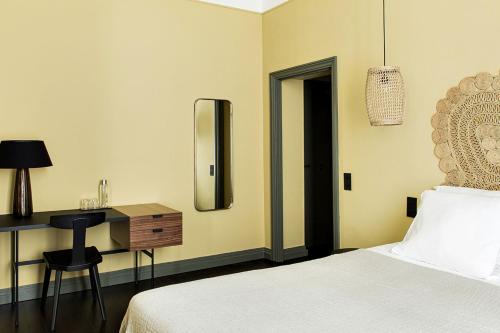 a bedroom with a bed and a desk with a mirror at New Hotel Le Quai - Vieux Port in Marseille