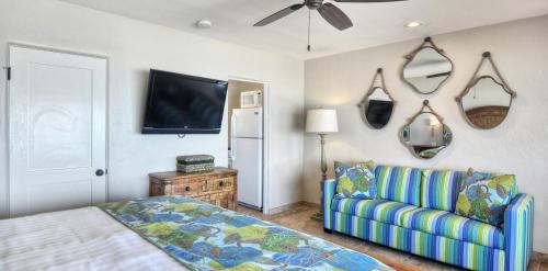 a bedroom with a couch and a tv on the wall at Beachcomber Inn in San Clemente