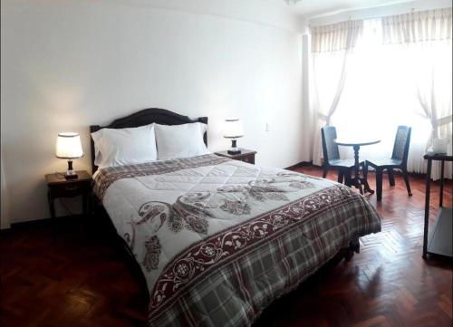 a bedroom with a bed and two chairs and a table at Hotel Glorioso in Oruro