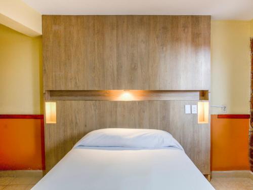 uma cama com uma cabeceira de madeira num quarto em OYO Hotel San Agustin em Acambay