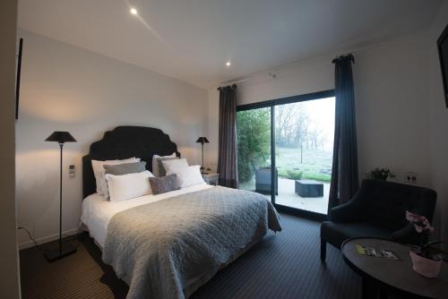 une chambre avec un lit, une chaise et une fenêtre dans l'établissement Hotel et restaurant Le Clos De La Prairie, à Gouy-Saint-André