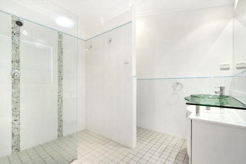 Un baño blanco con ducha y lavabo. en The Blue Cottage, en Ulladulla