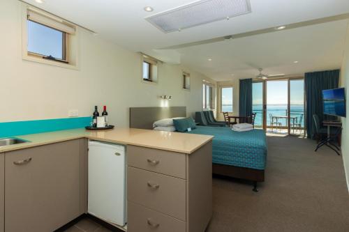 a room with a bedroom with a bed and a kitchen at The Dorsal Boutique Hotel in Forster