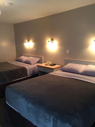 a hotel room with two beds and a desk at Ranchland Villa Motel in Merritt