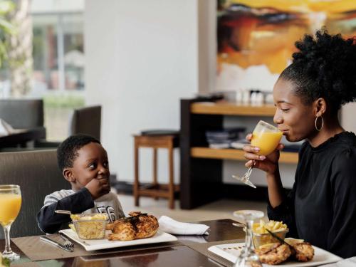 a woman and a child sitting at a table with orange juice at Pullman Lubumbashi Grand Karavia. in Lubumbashi