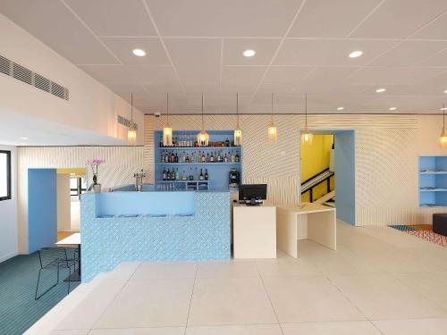 a lobby with a blue counter and a bar at Hôtel ibis Styles Auxerre Nord in Auxerre