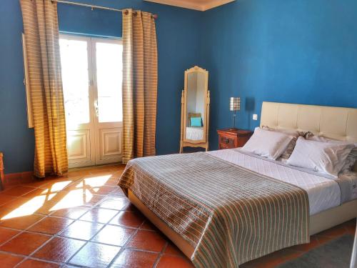 a bedroom with a bed with blue walls and a window at Monte Santa Catarina in Monsaraz