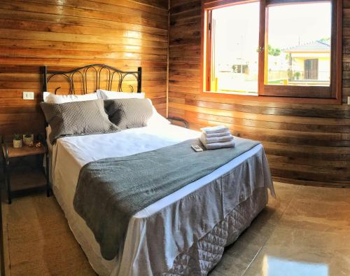 a bedroom with a bed in a wooden wall at Canyons Guest House in Praia Grande