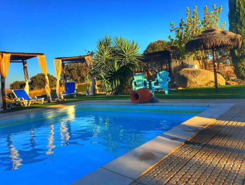 - une piscine avec des chaises bleues et un parasol dans l'établissement Monte Santa Catarina, à Monsaraz