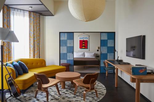 a living room with a yellow couch and a table at Ace Hotel Kyoto in Kyoto