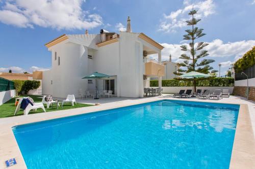 a villa with a swimming pool in front of a house at Villas Mar e Brisa in Albufeira