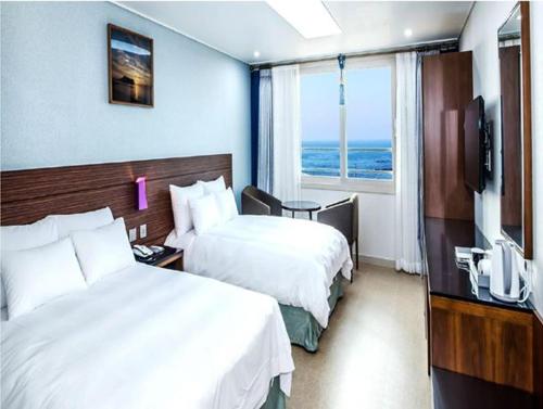 a hotel room with two beds and a television at The Stay Century Hotel in Jeju