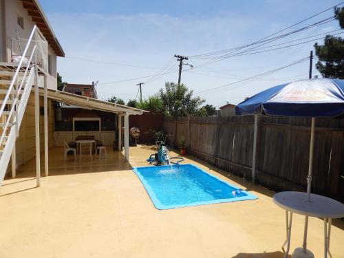 un patio trasero con piscina y sombrilla en El Galpon en Valeria del Mar