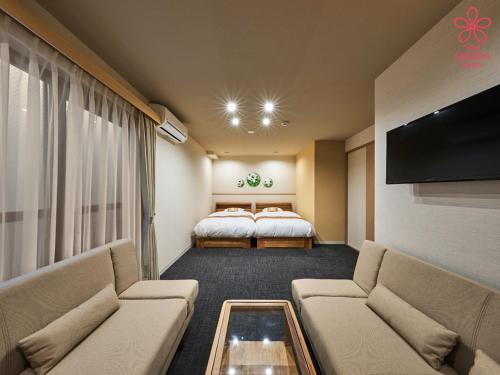 une chambre d'hôtel avec deux lits et un canapé dans l'établissement Stay SAKURA Kyoto Higashiyama Shirakawa, à Kyoto