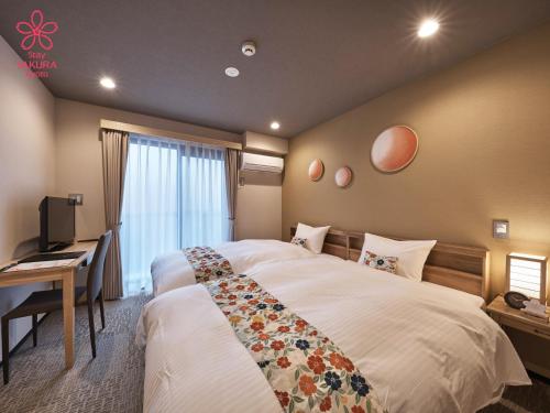 a bedroom with a large bed with a desk and a window at Stay SAKURA Kyoto Kiyomizu Gojo in Kyoto