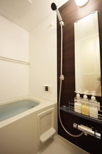 a bathroom with a tub and a sink and a mirror at Three Tokyo 102 in Tokyo