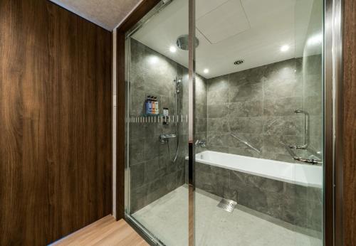 a bathroom with a shower and a tub and a sink at Daiwa Roynet Hotel Hakata Reisen PREMIER in Fukuoka