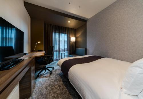 a hotel room with a bed and a desk with a computer at Daiwa Roynet Hotel Hakata Reisen PREMIER in Fukuoka