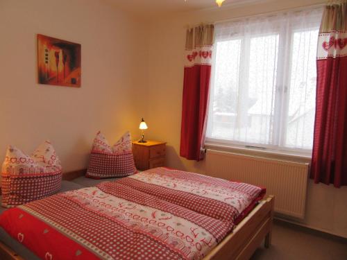 sypialnia z łóżkiem i oknem z czerwonymi zasłonami w obiekcie Haus Hasenmüller w mieście Schmiedefeld am Rennsteig