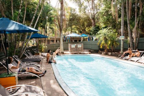 a group of people sitting around a swimming pool at Nomads Noosa in Noosa Heads