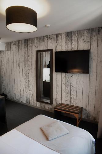 a bedroom with a bed and a tv on a wall at Nota Bene in Montceau-les-Mines