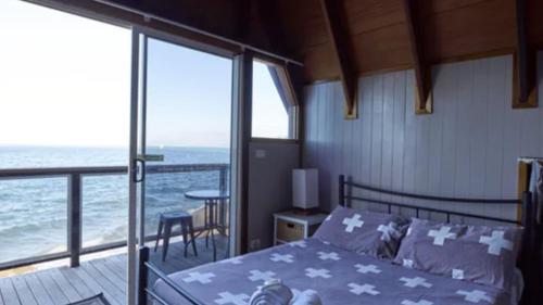 a bedroom with a bed and a balcony with the ocean at Nomads Magnetic Island in Nelly Bay