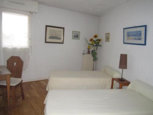 a bedroom with two beds and a table and a window at LOCBASQUE COM Appartement Résid Bidart Plage , classé meublé de tourisme 3 étoiles in Bidart