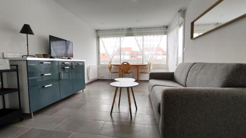 ein Wohnzimmer mit einem Sofa und einem Tisch in der Unterkunft Le Soleillades - Plage, piscine, parking! in Palavas-les-Flots