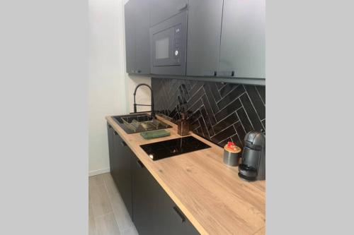 a kitchen with a wooden counter top with a microwave at Appart'TERRASSE - 20mn STADE U ARENA - CHAMPS ÉLYSÉES - RER A in Maisons-Laffitte