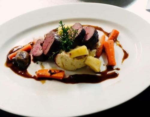 a white plate with meat and vegetables and gravy at Landgasthof Zum Kirchenwirt in Kellberg