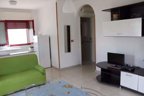 a living room with a green couch and a kitchen at Le sorgenti camere e appartamenti in Torre Vado