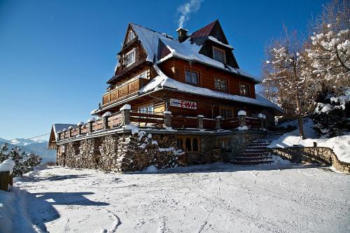 a large wooden house on top of a snow covered mountain at Dom Tatrzański Ewa in Kościelisko